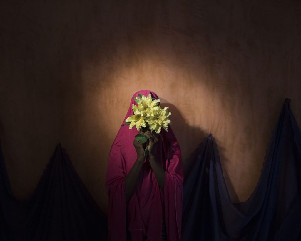 Falmata, age 15, stands for a portrait in Maiduguri, Borno State, Nigeria on Sept. 22, 2017. Falmata was kidnapped by Boko Haram then assigned a suicide bombing mission. After she was strapped with explosives, she found help instead of blowing herself and others up. Photo by Adam Ferguson for The New York Times